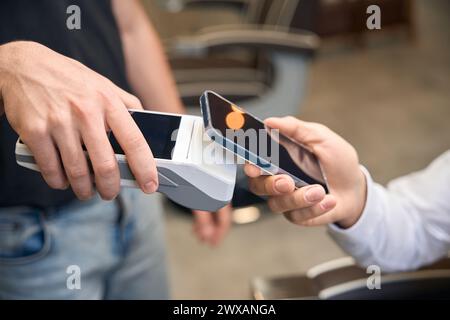 Male client making contactless paying with smartphone on pos terminal Stock Photo