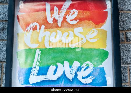 A we choose love sign on stone wall exterior depicting the LGTBQ rainbow colors Stock Photo