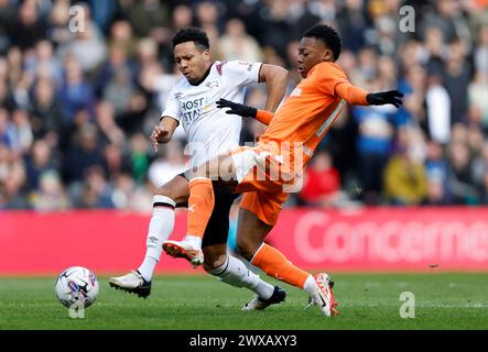 Derby County's Korey Smith (left) and Blackpool's Karamoko Dembele battle for the ball during the Sky Bet League One match at Pride Park Stadium, Derby. Picture date: Friday March 29, 2024. Stock Photo