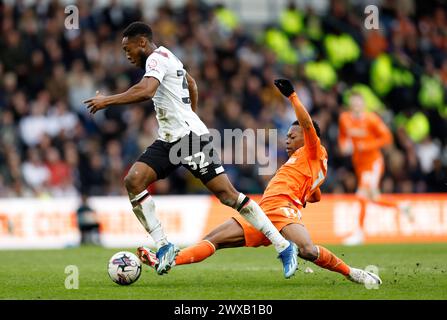 Derby County's Ebou Adams (left) is tackled by Blackpool's Karamoko Dembele during the Sky Bet League One match at Pride Park Stadium, Derby. Picture date: Friday March 29, 2024. Stock Photo