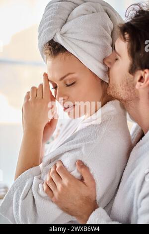 Couple in love in bathrobes, hugging each other, man kissing his girlfriend tenderly Stock Photo