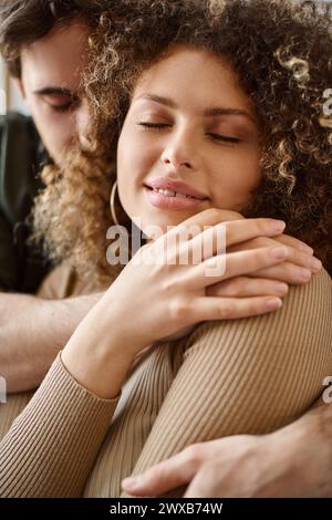 Closeup image of curly young woman and brunette man sharing a heartfelt hug in bedroom Stock Photo