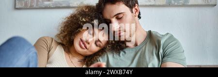 In their cozy bedroom, curly young woman and brunette man sharing a heartfelt hug, banner Stock Photo