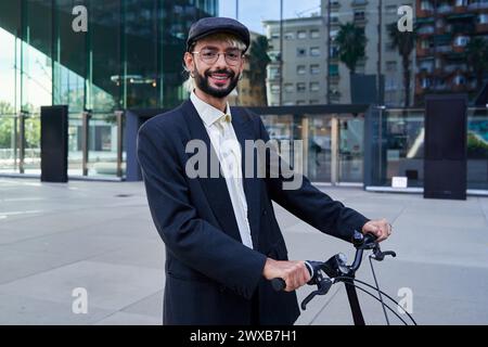 Hipster businessman looking at camera smiling, using a bicycle to transport himself to work. Stock Photo