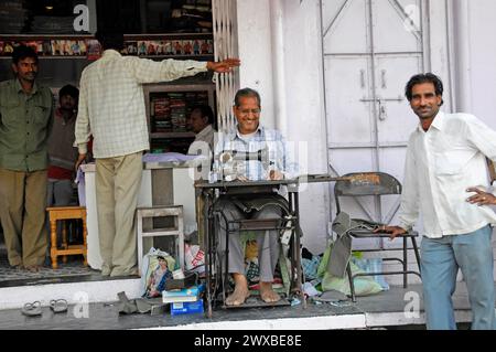 A man working on an old sewing machine in front of a shop on the street, Udaipur, Rajasthan, North India, India Stock Photo