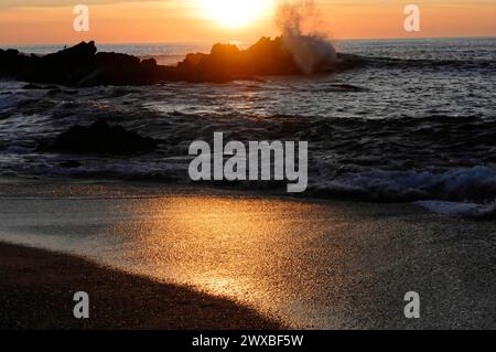 Waves crashing against rocks in the sea during a sunset, creating a dynamic and powerful image, near Mindelo, Porto, Northern Portugal, Portugal Stock Photo