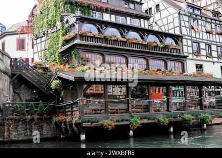 Boat trip on the L'ILL, Strasbourg, Alsace, A traditional restaurant with half-timbered houses and a terrace full of flowers by the water Stock Photo