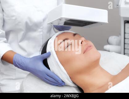 The cosmetologist uses the Wood Lamp for detailed diagnosis of the skin condition. The device detects the presence of skin diseases or inflamed areas. Stock Photo