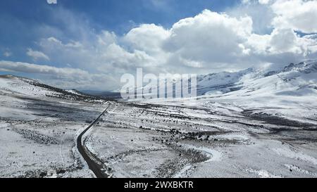 Snow-covered road winding through a valley with no traffic Stock Photo
