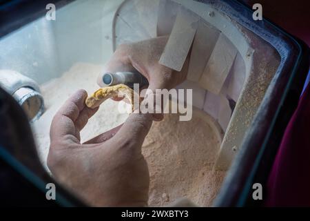 A dental technician seen from above polishes the details of a dental stone model with the handpiece to make it ready to work on. Stock Photo