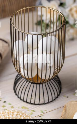 Modern wire basket full of white bath bombs on wooden table Stock Photo