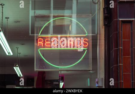 A neon sign that reads records in the window of a record shop. Record store day, vinyl record sales, music industry or record collecting concept. Stock Photo