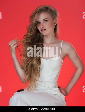 Portrait of young blonde woman dressed in white sculpted corset top. Headshot of young female fashion model from Gen Z with long, wavy blonde hair Stock Photo