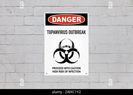 Warning sign screwed to a brick wall to warn about a health hazard. In the middle of the panel, there is a biohazard symbol and the message is saying Stock Photo