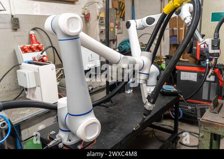 A modern welding robot in an old crowded welding workshop Stock Photo