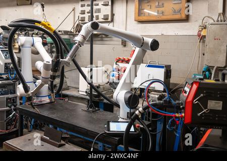 A modern welding robot in an old crowded welding workshop Stock Photo