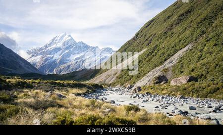 Scenic alpine valley with glacial river flowing through and prominent peak in backdrop, New Zealand. Stock Photo