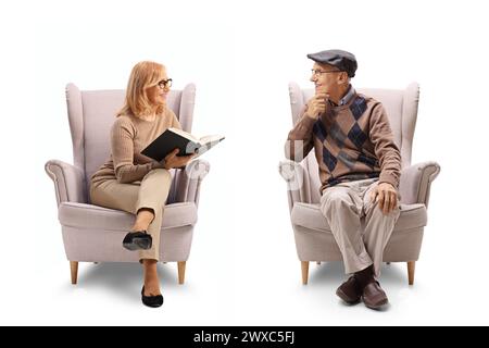 Mature woman holding a book and talking to a man seated in an armchair isolated on white background Stock Photo