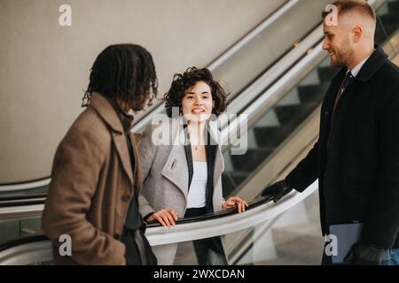 Business colleagues conversing and smiling on an escalator in modern building. Stock Photo