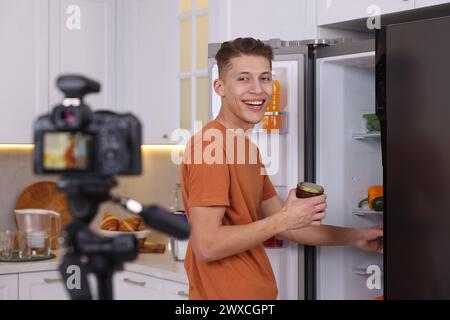 Smiling food blogger explaining something while recording video in kitchen Stock Photo