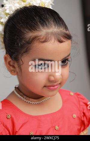 A cute small girl child wearing  Kerala dress-golden colour long skirt and red blouse, isolated image with white background. Stock Photo