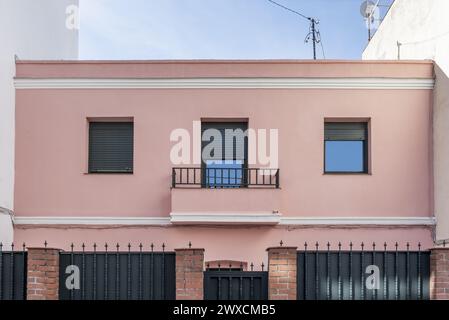 Facade of a pale pink single-family residential home and perimeter fence Stock Photo