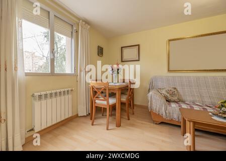 Cherry wood dining table with matching chairs, a coffee table and an armchair in the corner of the living room of a house Stock Photo