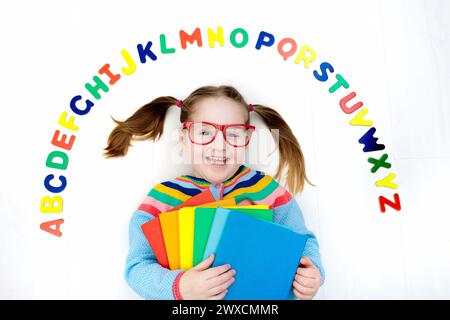 Happy preschool child learning to read and write playing with colorful roman alphabet letters. Educational abc toys and books for kids. School student Stock Photo