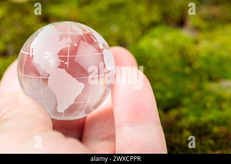 Transparent Glass Globe Held in Man's Palm, Concept of Earth Day and Environmental Protection Stock Photo