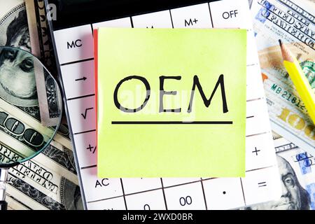 OEM original equipment manufacturer concept. Text on a yellow sticker on the calculator against the background of banknotes Stock Photo