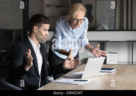 Two excited worried younger and elder business colleagues using laptop Stock Photo