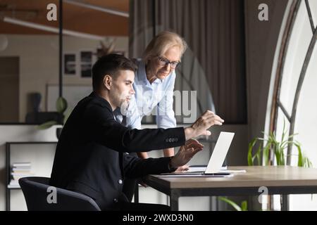 Two younger and elder business professionals discussing project tasks Stock Photo