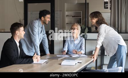 Cheerful diverse team brainstorming on project, discussing successful marketing reports Stock Photo