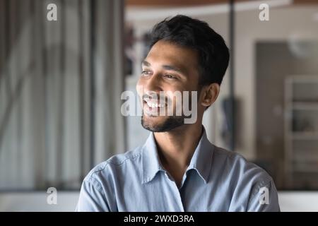 Cheerful young Indian man looking at window away Stock Photo