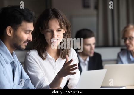 Multiethnic couple of positive colleagues talking at laptop Stock Photo