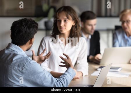 Young Indian project manager explaining creative ideas to female colleague Stock Photo