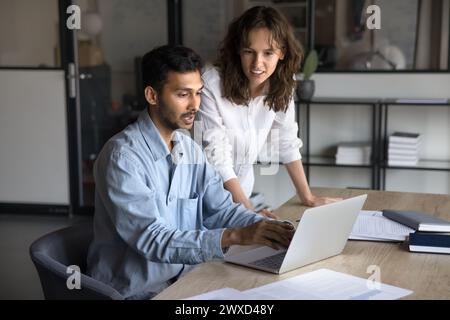 Focused young multiethnic coworkers discussing online project Stock Photo