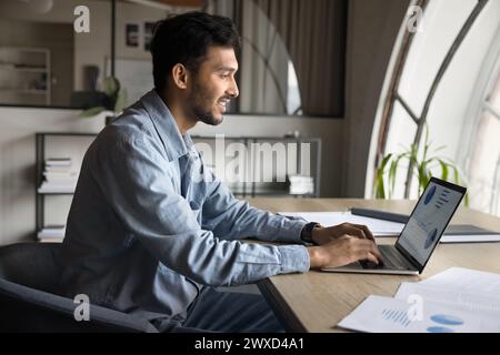 Happy Indian entrepreneur man analyzing marketing charts, financial data Stock Photo