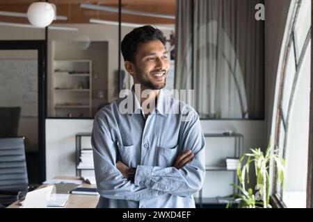 Cheerful handsome young Indian manager man standing in office Stock Photo
