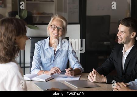 Positive senior mentor woman training group of young employees Stock Photo