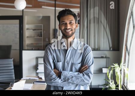 Happy successful attractive Indian business man standing in office Stock Photo
