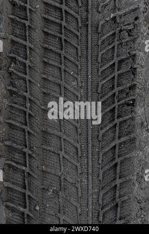 Traces of car tire tread in the ground. Pattern. Dark abstract background. Imprint of wheels. Textured soil. Drawing tires. Stock Photo