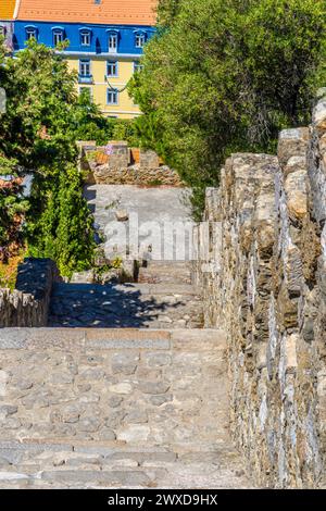 Walls and stairs of St. George's Castle leading to typical blue and yellow houses of Lisbon, Portugal. Stock Photo