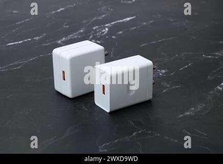 white smartphone chargers on the black marble background Stock Photo