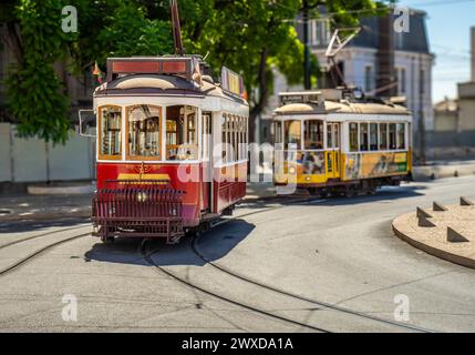 Famous and typical vintage old red tram, beautifully decorated and retaining the original designs running on the tracks in a typical Lisbon street in Stock Photo