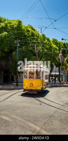 Famous and typical old yellow tram, beautifully decorated and preserving the original designs traveling uphill on the tracks of a typical Lisbon stree Stock Photo