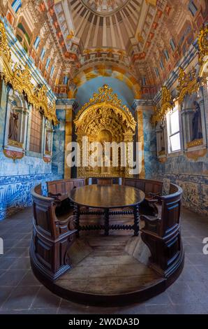 Luxuriously decorated living room with a wooden table, chapel with golden motifs with the statue of Saint Francis, blue tiles and religious sculptures Stock Photo