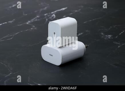 white smartphone chargers on the black marble background Stock Photo