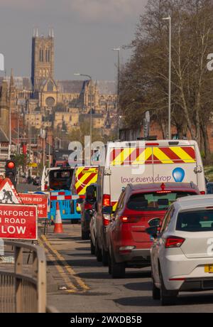 Road works, re-surfacing, carriageway, stone chippings, grit, sweeper, roller, vehicle, skidding, red warning sign, footway works, Lincoln, Cathedral. Stock Photo