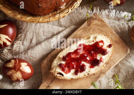 A slice of Czech sweet Easter cake called mazanec with butter and cranberry jam on a wooden cutting board Stock Photo